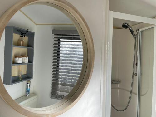 a round mirror in a bathroom with a window at Little Owl - Holiday Home - Caravan Break in Tunstall