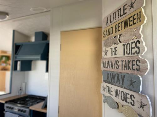 a kitchen door with a sign that reads smile shall be answered the toes knows likes at Little Owl - Holiday Home - Caravan Break in Tunstall