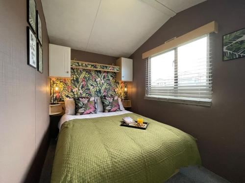 a bedroom with a large bed with a green bedspread at Little Owl - Holiday Home - Caravan Break in Tunstall