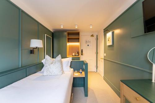 a bedroom with a bed and a table with a lamp at The Goodenough Hotel London in London