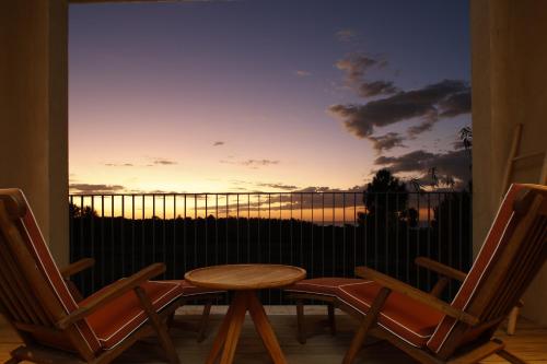 a table and chairs on a balcony with a sunset at Praia do Canal Nature Retreat - Small Luxury Hotels of the World in Aljezur