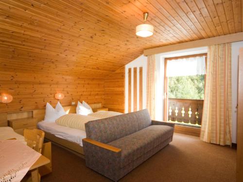 a bedroom with a bed and a couch and a window at Pension & Appartament Anna in Predoi
