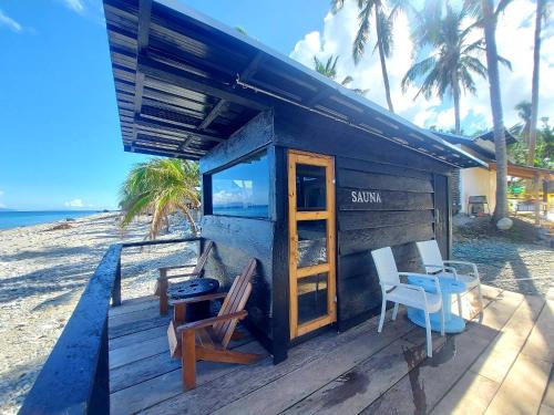 a house on the beach with two chairs and a table at Surigao Dream Beach Resort in Tigbao