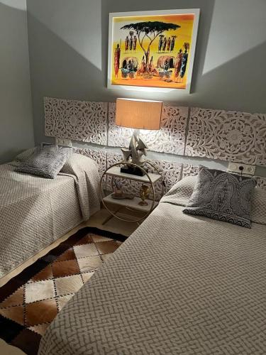 a bedroom with two beds and a table with a lamp at Flamingo Apartment Coto Real La Duquesa in Manilva