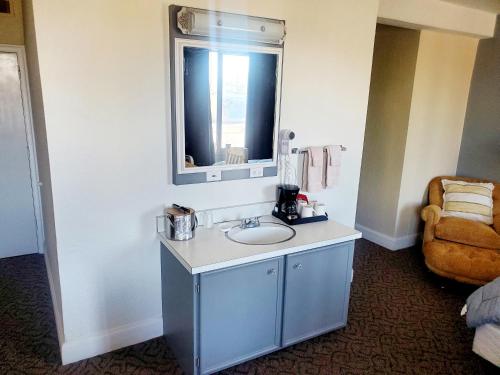 ein Badezimmer mit einem Waschbecken, einem Spiegel und einem Stuhl in der Unterkunft Monte Villa Hotel in Monte Vista