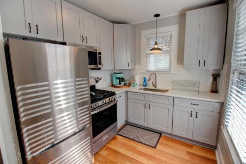 a kitchen with white cabinets and a stainless steel refrigerator at Heart of Galveston Stylish Apt Near Attractions in Galveston