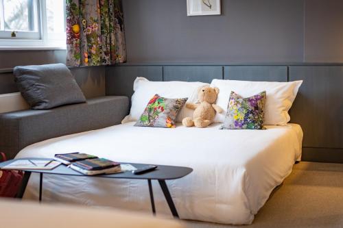 a teddy bear sitting on a bed with pillows at The Goodenough Hotel London in London