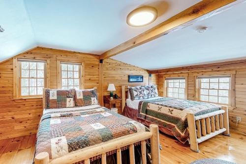 a log cabin bedroom with two beds and windows at Great Pond House in Belgrade