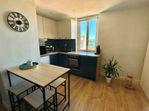 a kitchen with a table and a clock on the wall at IVS Andreossy Vue mer et montagne pour 4 in Antibes