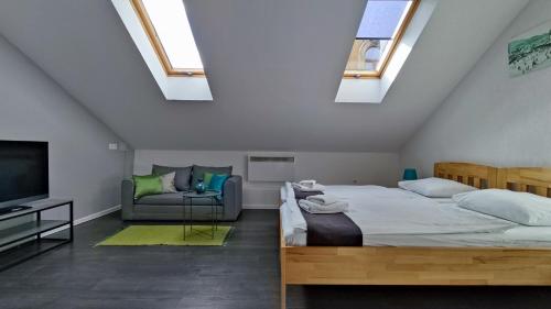 a bedroom with a bed and a couch and skylights at Apartments Protin sokak in Sarajevo