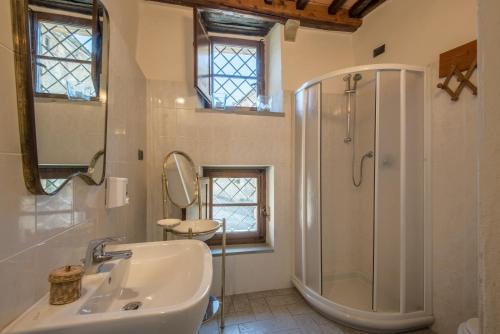 baño blanco con ducha y lavamanos en Casale Rosennano - Scuderie, en Rosennano