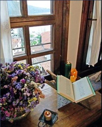 a book and a vase of flowers next to a window at Vergoula's Mansion in Kastoria
