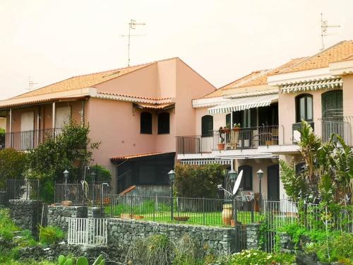 uma casa cor-de-rosa com uma vedação à frente. em Casa sul mare in Sicilia, Acireale-Stazzo em Acireale