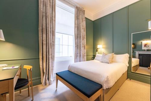 a bedroom with a bed and a desk and a window at The Goodenough Hotel London in London
