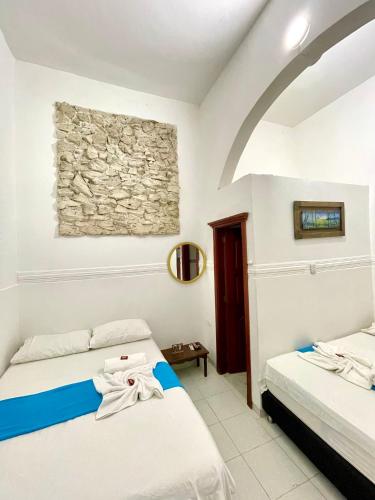 a bedroom with two beds and a stone wall at Hotel Mangata in Cartagena de Indias