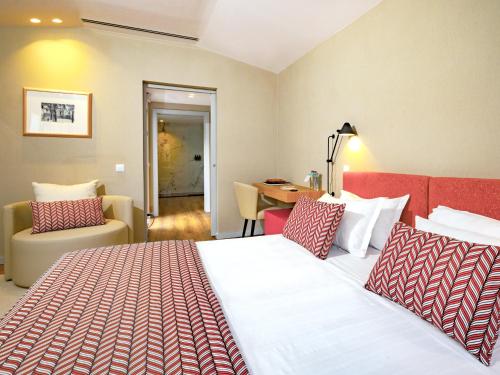 a hotel room with a bed and a chair and a table at Central Monchique Hotel - Villa Termal Spa Resort - by Unlock Hotels in Monchique