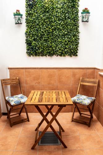 a wooden table and two chairs in front of a hedge at Casa Rural Los Eneares in Ossa de Montiel