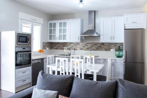a kitchen with white cabinets and a table and a couch at Casa Rural Los Eneares in Ossa de Montiel