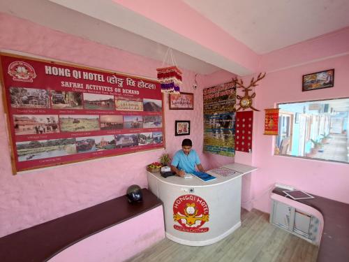 a boy sitting at a counter in a pink room at Hong Qi Hotel in Chitwan