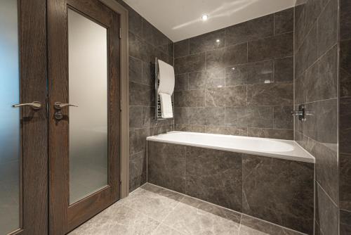 a bathroom with a tub and a mirror at Dakota Eurocentral in Motherwell