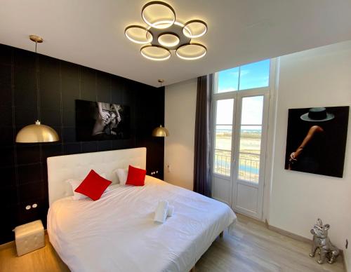 a bedroom with a large white bed with red pillows at La Vague Tendresse - Vue mer - Jacuzzi & Sauna in Le Tréport