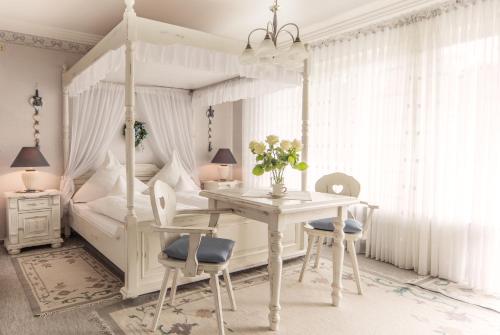 1 dormitorio con cama con dosel, mesa y sillas en Ambient Hotel am Europakanal, en Fürth