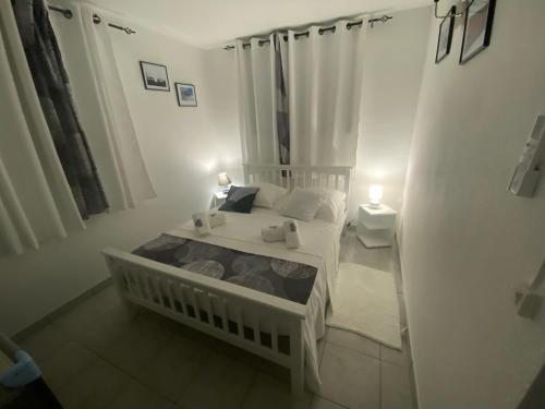 a small bedroom with a white bed and two lamps at COIN D ARMANTINE in Capesterre-Belle-Eau