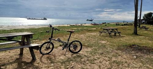 a bike parked next to a picnic table and the ocean at Syah Homestay in Dungun