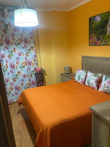 a bedroom with an orange bed with a flowered curtain at Apartamento Carmona in Carmona