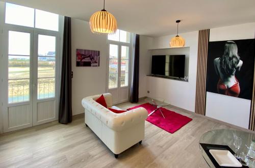 a living room with a white couch and a tv at La Vague Tendresse - Vue mer - Jacuzzi & Sauna in Le Tréport
