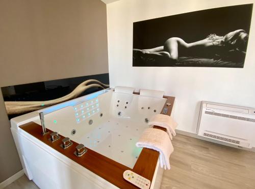 bañera de hidromasaje en una habitación con una foto en la pared en La Vague Tendresse - Vue mer - Jacuzzi & Sauna, en Le Tréport