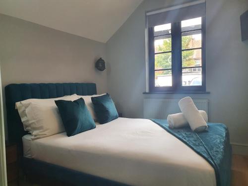 a bed with blue and white pillows and a window at Lovely 1-Bedroom GF flat in Canford Cliffs in Canford Cliffs