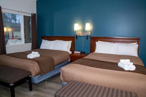 two beds in a hotel room with towels on them at Spanish Villa Resort in Penticton