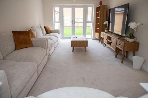 a living room with a couch and a tv at 7 Swiftsure - 4 Bedroom Luxury and Spacious Home in Milton Keynes