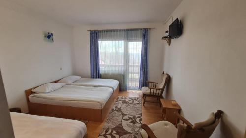 a small room with two beds and a window at Pensiune Runcu Stone in Runcu