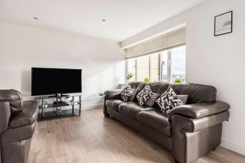 sala de estar con sofá de cuero y TV de pantalla plana en Stunning Flat by Quayside with Balcony!!, en Newcastle