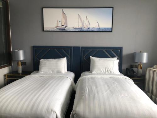 2 Betten in einem Zimmer mit Segelbooten an der Wand in der Unterkunft Apartment in Arena Cam Ranh near the airport in Cam Ranh