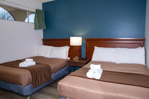 two beds in a hotel room with towels on them at Spanish Villa Resort in Penticton