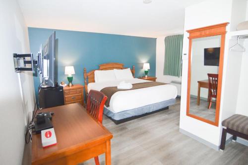 a bedroom with a bed and a desk and a table at Spanish Villa Resort in Penticton