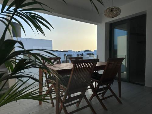 una mesa de madera y sillas en un balcón con una planta en Casa Nordeste con piscina Casilla de Costa, en La Oliva