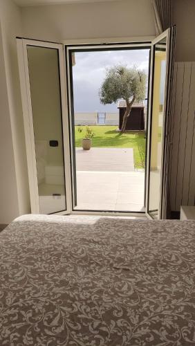 a bedroom with a large sliding glass door to a yard at Camera sul Mare in Messina