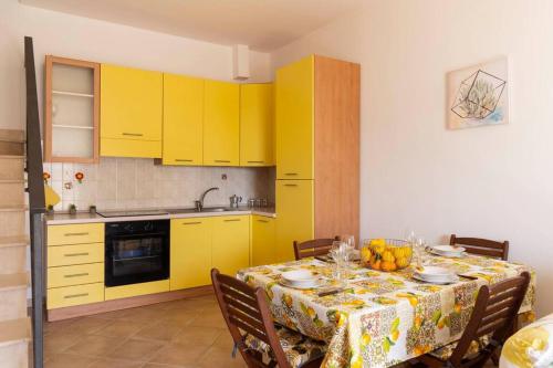 kuchnia z żółtymi szafkami i stołem z tkaniną w obiekcie Villa vista mare ~Villa Dafne~ w mieście Noto Marina