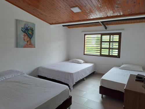 a bedroom with two beds and a window in it at Casa de Campo Las Partidas in Quimbaya