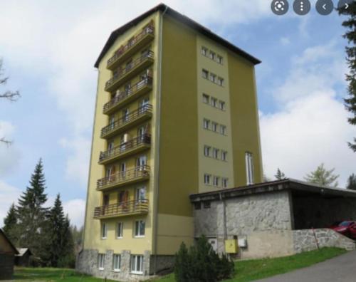 a tall yellow building with balconies on it at Útulný 3-izbový byt v srdci Tatier in Vysoké Tatry