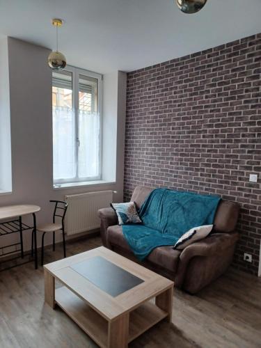 a living room with a couch and a brick wall at Chez Arthur et Cie in Luxeuil-les-Bains