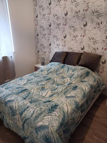ein Bett mit einer blauen und weißen Bettdecke in einem Schlafzimmer in der Unterkunft Chez Arthur et Cie in Luxeuil-les-Bains