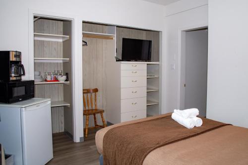 a bedroom with a bed with a microwave and a television at Spanish Villa Resort in Penticton