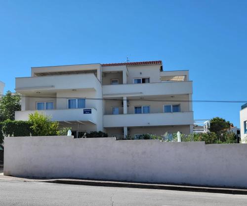 a white building with a fence in front of it at Apartments Marti in Murter