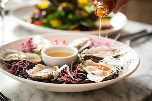 a bowl of oysters with a dipping sauce at Kimpton Hotel Fontenot by IHG in New Orleans