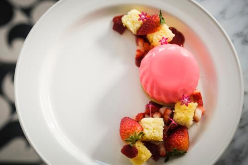 a white plate with strawberries and a pink dessert at Kimpton Hotel Fontenot by IHG in New Orleans